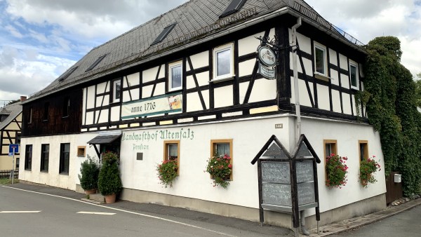 Zweistöckiges weißes Fachwerkhaus mit schwarzen Balken an ruhiger Straße